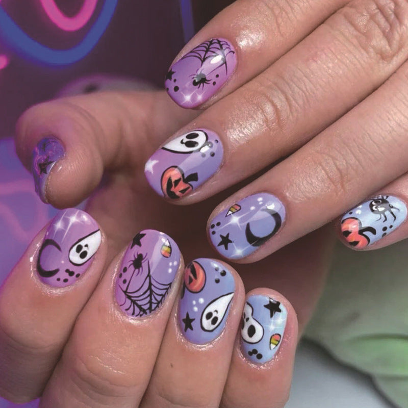 A set of purple press-on nails with various Halloween-themed designs including ghosts, pumpkins, and moons.