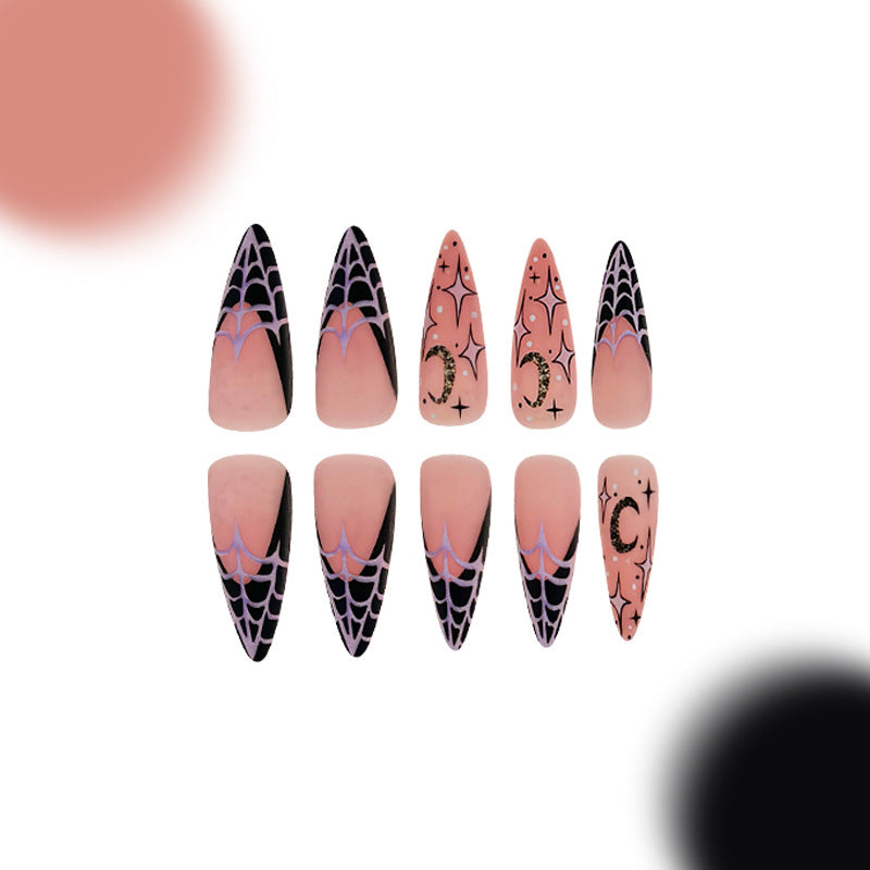 A set of long, stiletto press-on nails with a spooky glam design featuring pink and black colors, and decorations that include stars and the letter 'C' in sparkling fashion.