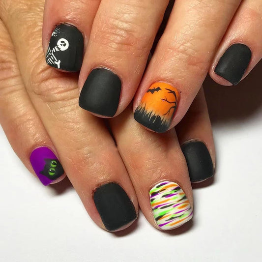 A set of press-on nails featuring a combination of black, orange, purple, and green colors with decorations of bats and a pumpkin.