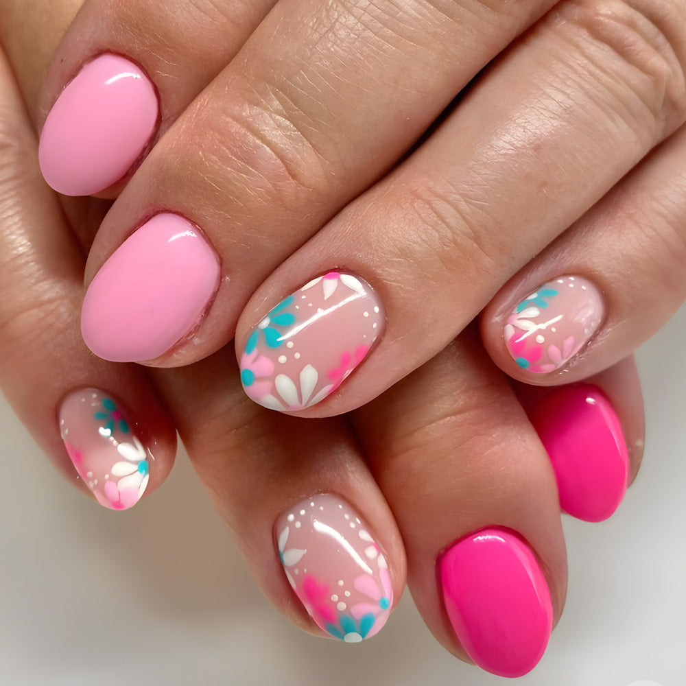 Close-up of a hand with pink and floral nail design on a neutral background