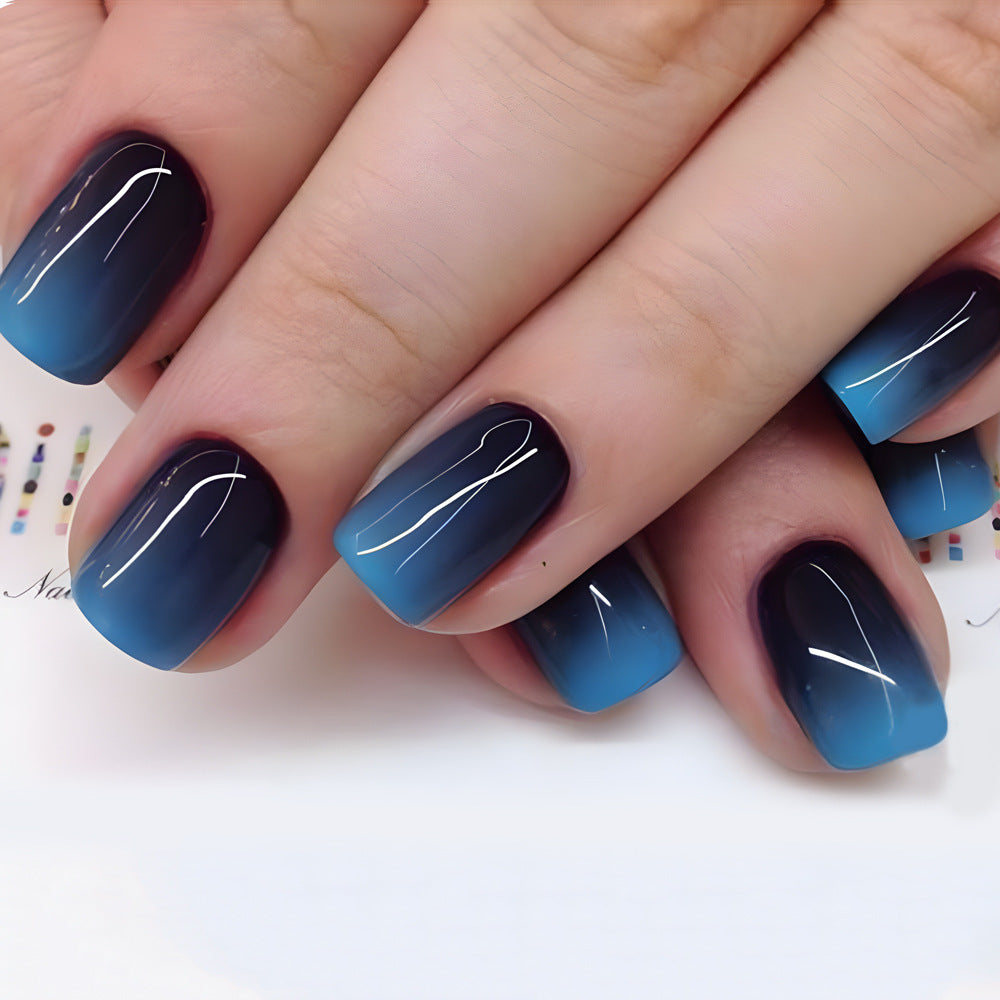 Close-up of a hand with blue and black gradient nail polish on a white background