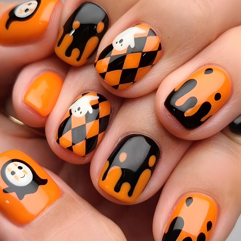A set of press-on nails featuring a geometric pattern with orange, black, and white colors, and decorative ghost and pumpkin designs.