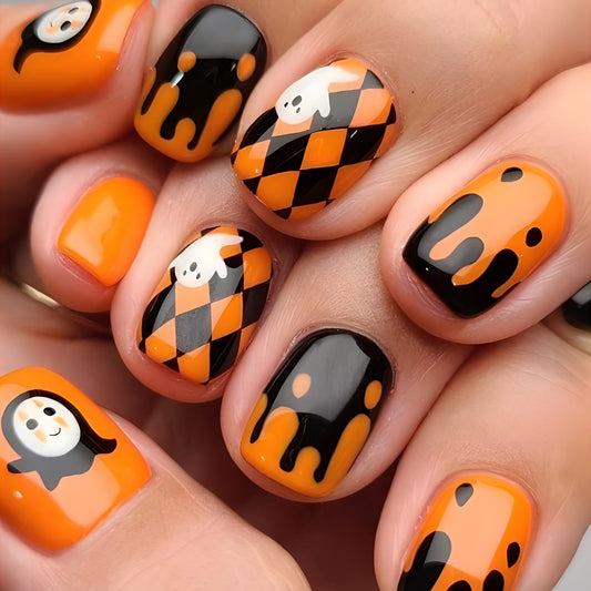 A set of press-on nails featuring a geometric pattern with orange, black, and white colors, and decorative ghost and pumpkin designs.