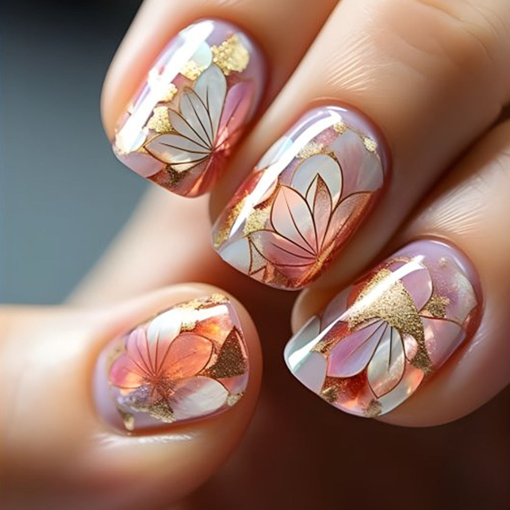 Nails with floral design and gold accents on a neutral background