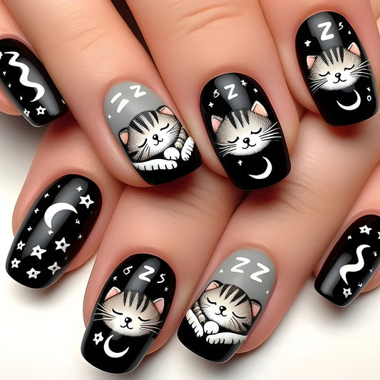 A set of press-on nails featuring medium length square shapes with black and gray color schemes, adorned with whimsical cat designs and sleep-themed elements like moons and stars.