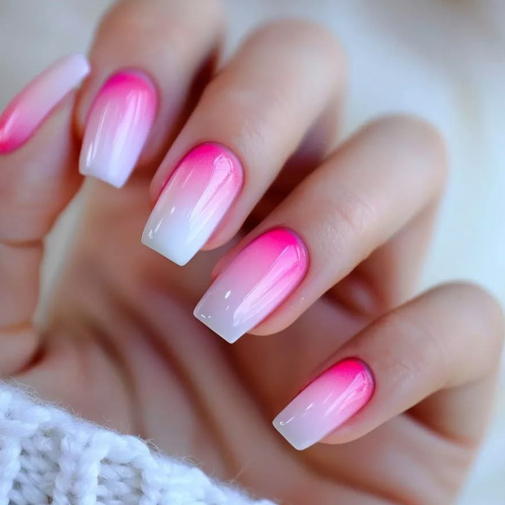 Hand with pink and white gradient nail polish on a blurred background