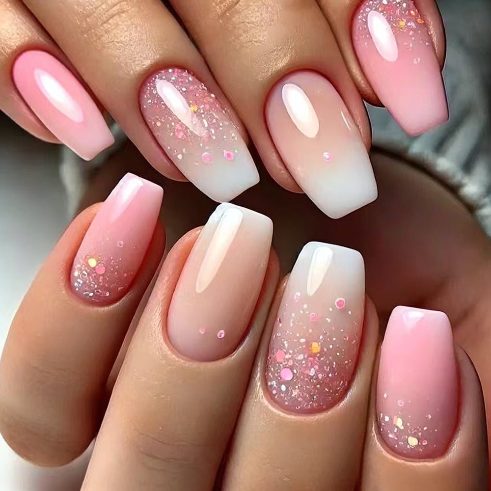 Close-up of hands with pink and white gradient nails with glitter.