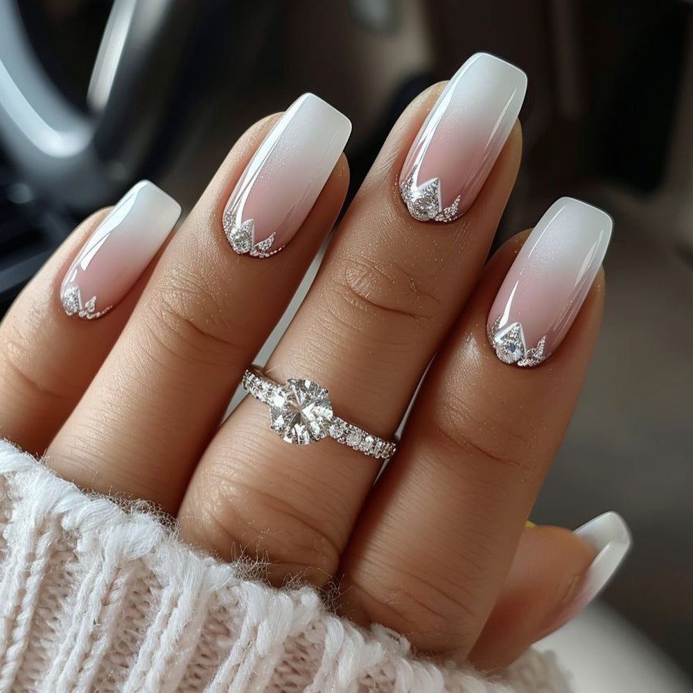 Hand with gradient nail design and diamond accents, wearing a ring.