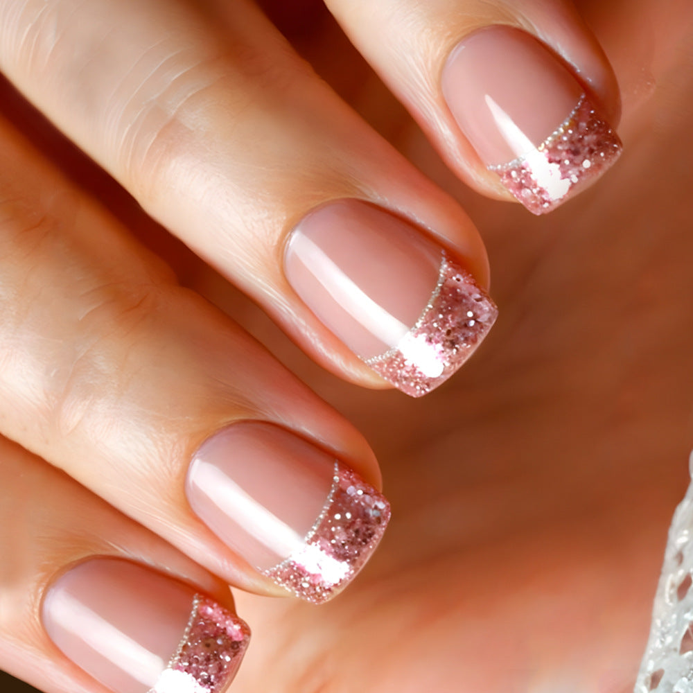 Close-up of a hand with pink nails and glittery accents on a blurred background