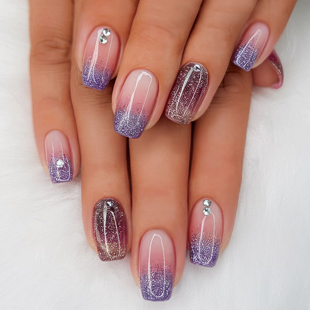 Nails with gradient design and glittery accents on a white background