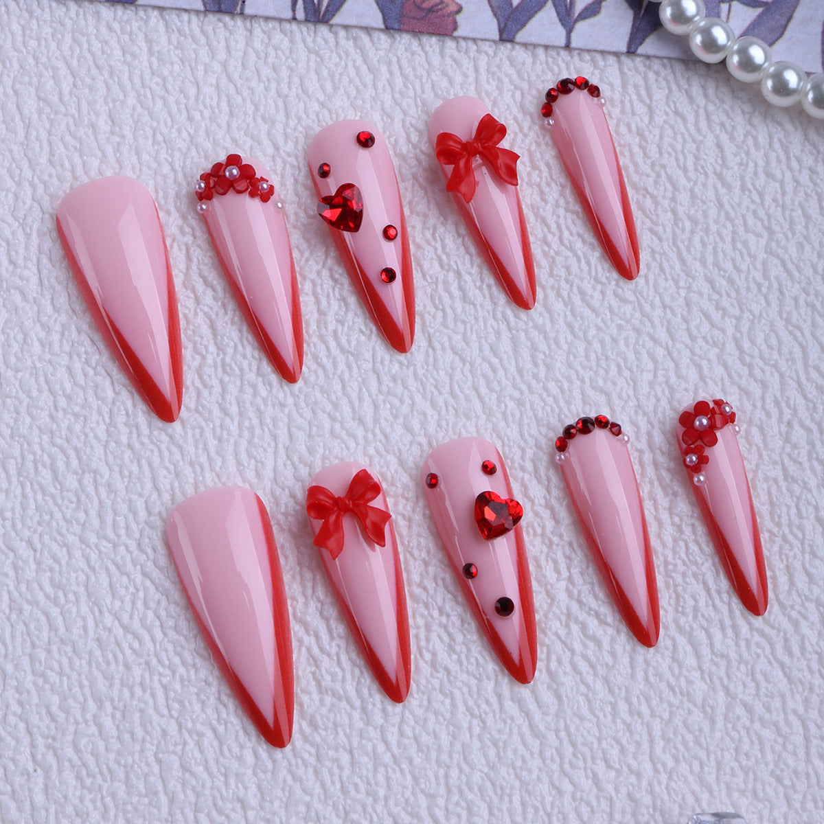 Romantic Charm Long Almond Pink Nails with Red Accents and Decorative Embellishments
