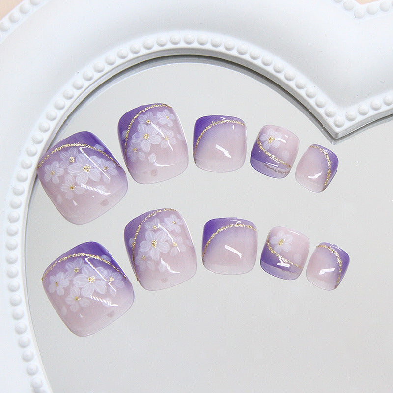Set of purple and gold floral nail art on a white heart-shaped tray