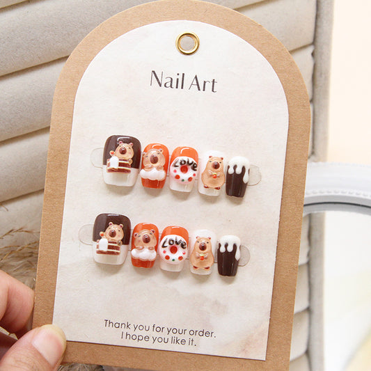 A set of square press-on nails featuring cute bear designs in shades of orange, brown, and white, displayed on a card.