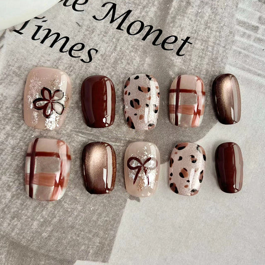A collection of press-on nails featuring a variety of designs including solid colors, animal prints, and decorative patterns placed on a newspaper.