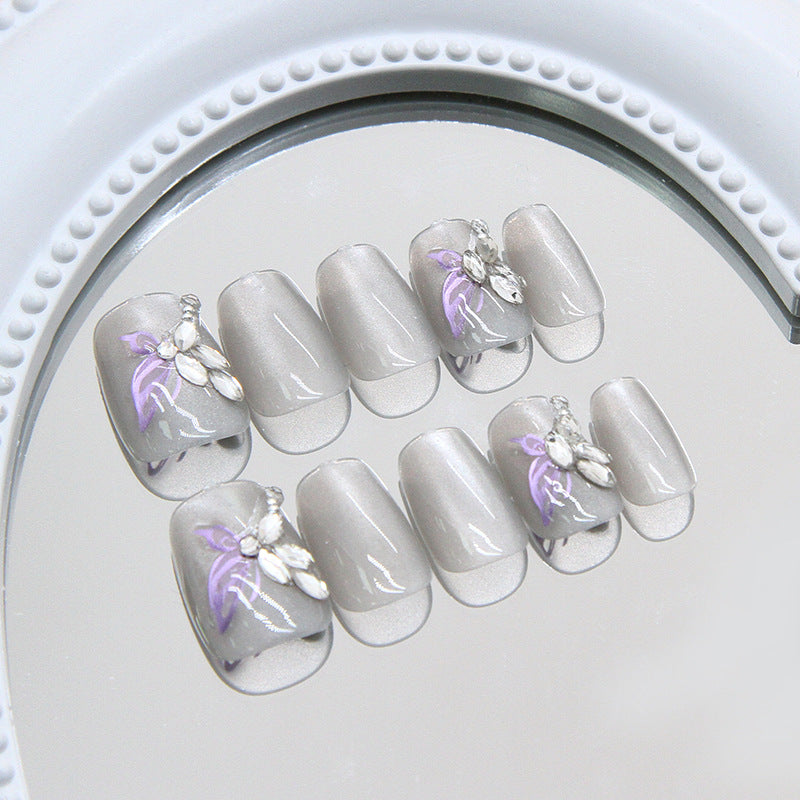 Set of gray false nails with floral designs on a mirror surface