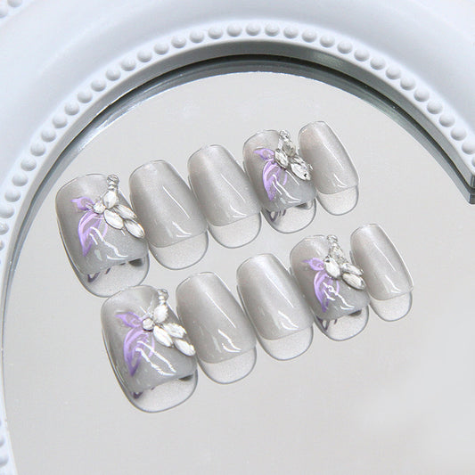 Set of gray false nails with floral designs on a mirror surface