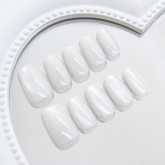 Set of white press-on nails on a white tray with decorative edge