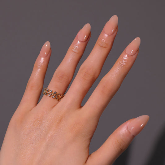 Hand wearing a gold ring with small stones on a gray background