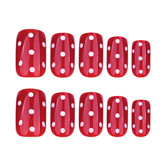 A set of red false nails with white polka dots, arranged in a squoval shape.