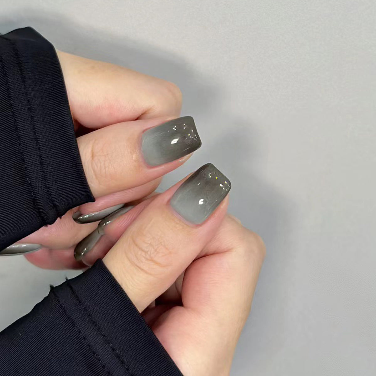 Close-up of a hand with gray nail polish on a plain background