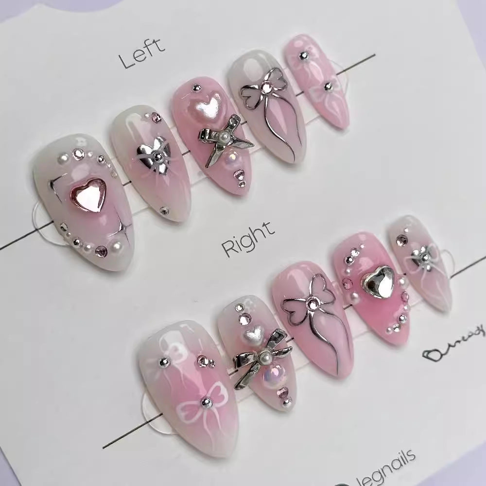 A set of long almond shape press on nail sets with heart and bow decorations, predominantly in pink color.