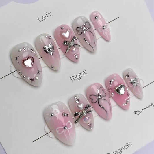 A set of long almond shape press on nail sets with heart and bow decorations, predominantly in pink color.