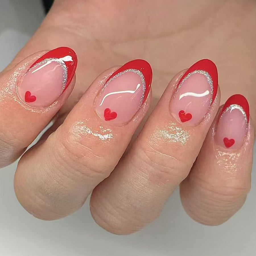 Nails with red and clear design featuring small hearts on a neutral background