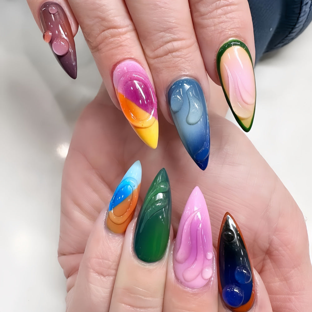 A set of colorful, long stiletto press-on nails with unique swirl designs, displayed on a person's hands.