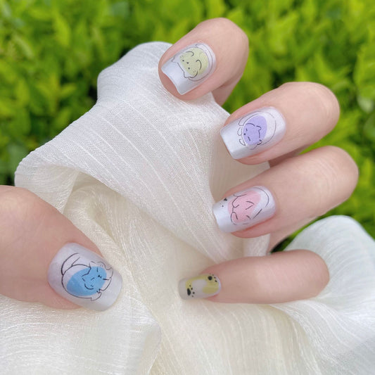 A set of nails with press-on extensions featuring adorable cat faces in various pastel colors.