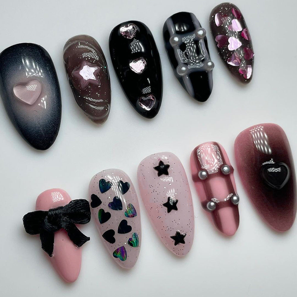 A collection of press-on nails featuring various designs including hearts and bows in black and pink colors.