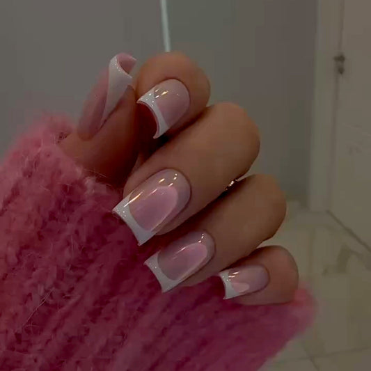 A pair of pink and white fingernails with a glossy finish, shown on a hand wearing a pink sweater.