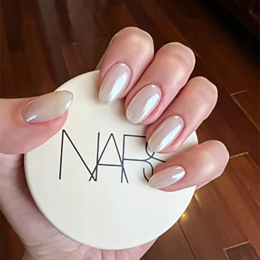 Hand holding a NARS makeup compact with a blurred background