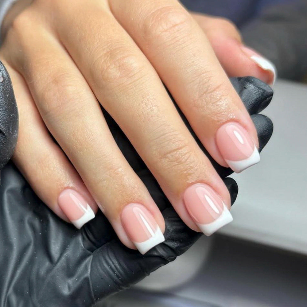 A pair of pink and white press-on nails with a glossy finish, displayed on a hand.