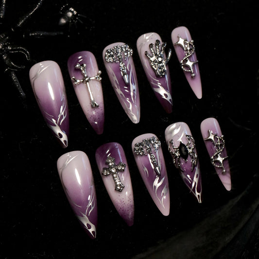 A set of long stiletto purple press-on nails with silver charm embellishments.