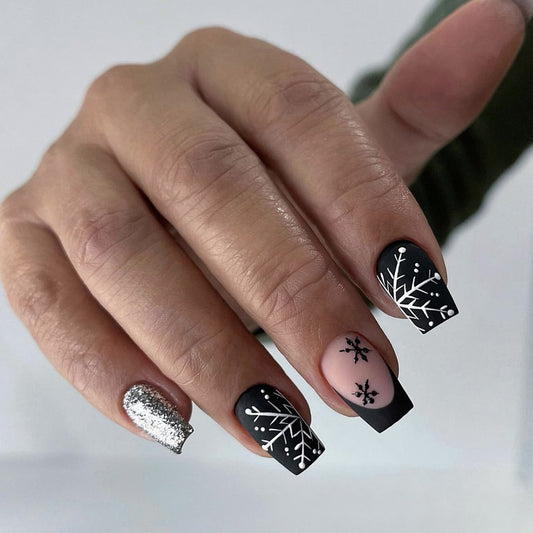 A set of press-on nails featuring a snowflake design with black and pink coloring and a sparkling accent nail.