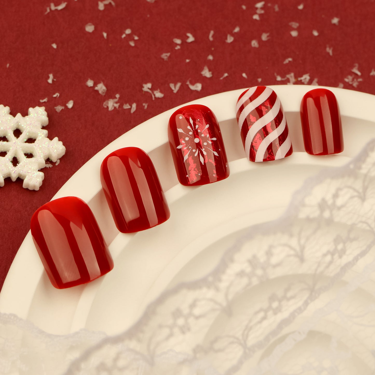 Red nail art designs on a textured white surface with a red background