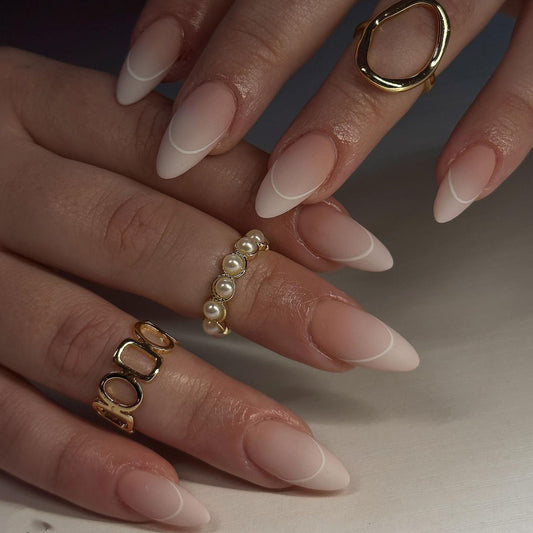 Close-up of hands with gold and pearl rings on a neutral background