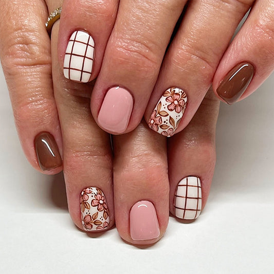 Close-up of a hand with brown and pink nail designs on a white background
