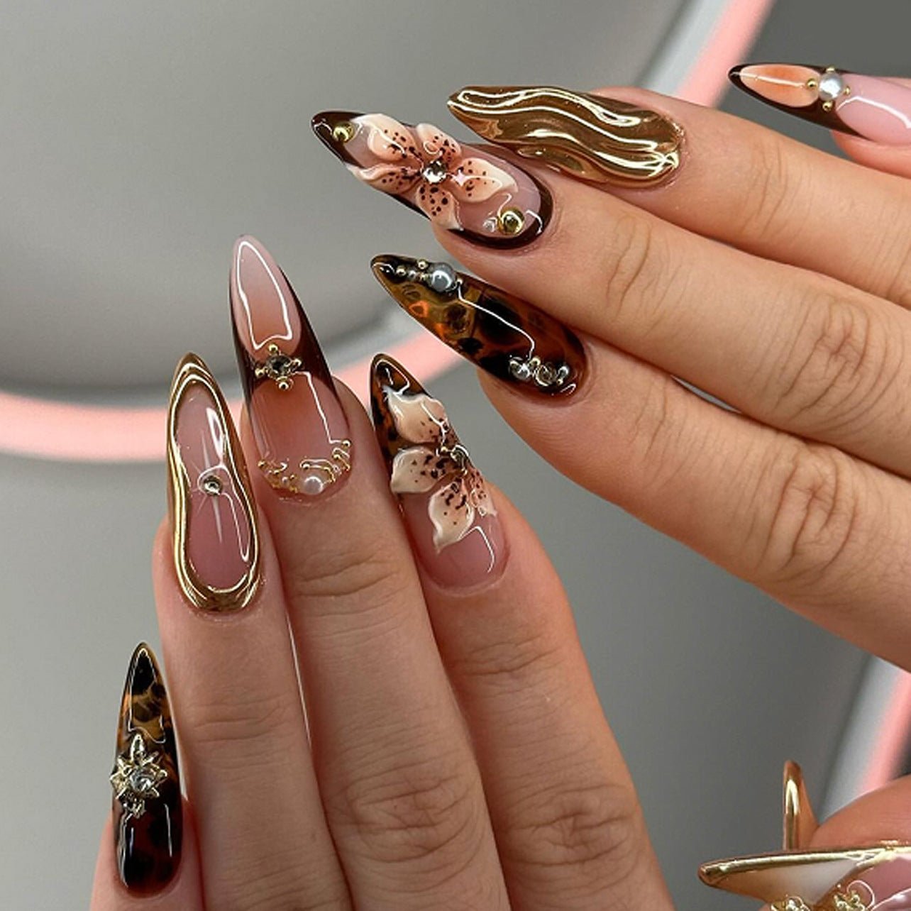 Close-up of hands with long, intricately designed nails featuring floral and abstract patterns.