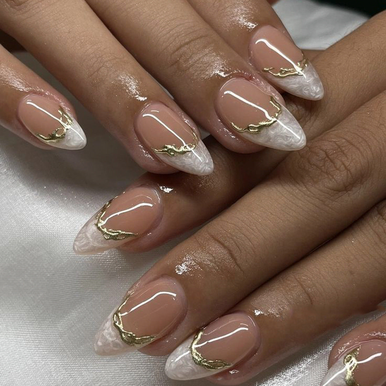 Nails with gold leaf design on a white background