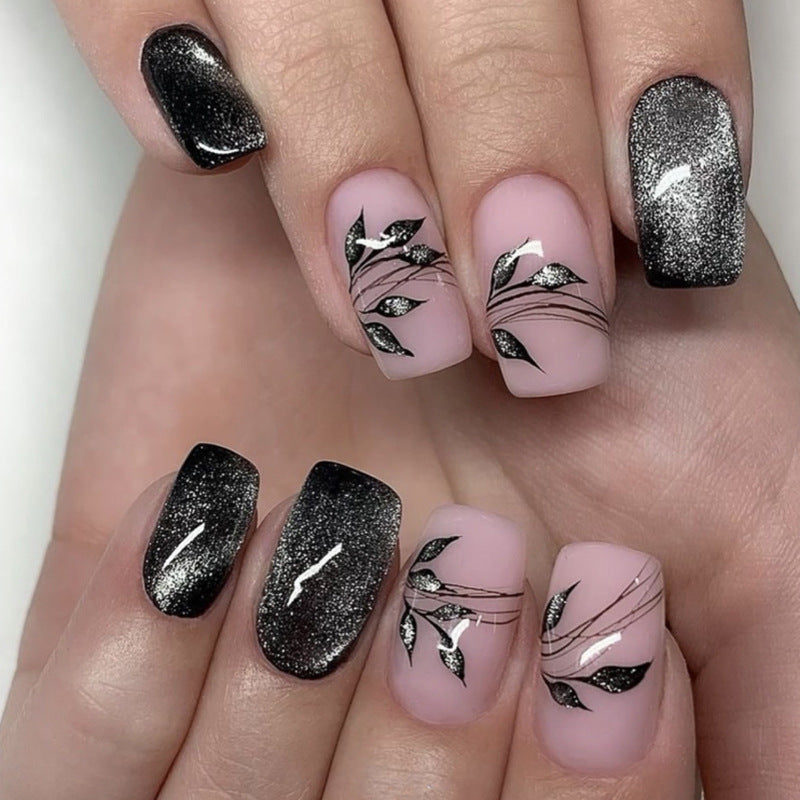 Nails with pink polish and black leaf designs on a white background