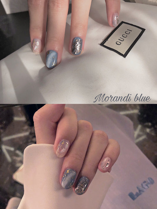 A photo showing a pair of hands with short square blue glitter press-on nails, with a focus on the nail design.