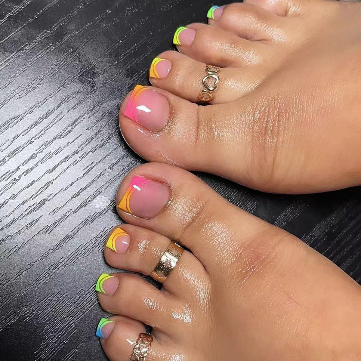 A set of press-on toenails with a dual-tone design, featuring a mix of neon colors and a short square shape.