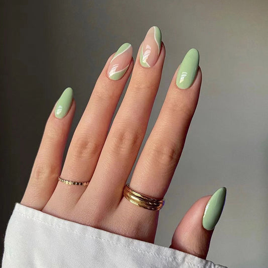 A person's hand with short square green summer press on nails, showing a manicure with a green gradient design.