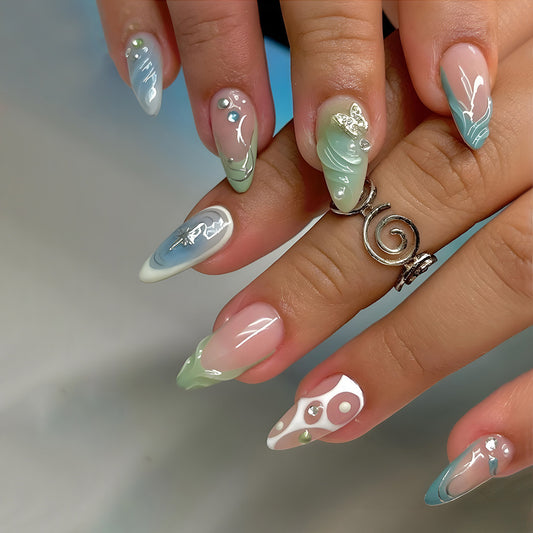A set of almond-shaped press-on nails featuring a gradient of green and white with unique swirl designs and teardrop accents.