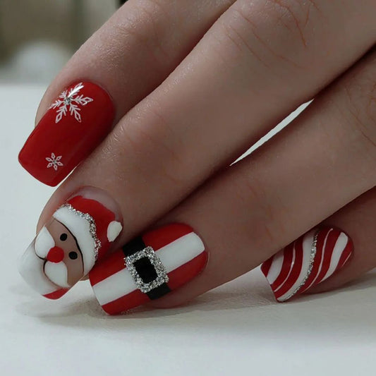 A set of red nails with a Christmas-themed design, featuring a cartoon depiction of Santa Claus and snowflakes.