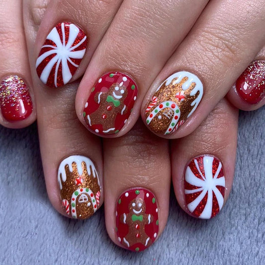 Nail art with Christmas-themed designs including gingerbread men, candy canes, and gingerbread houses on a neutral background.