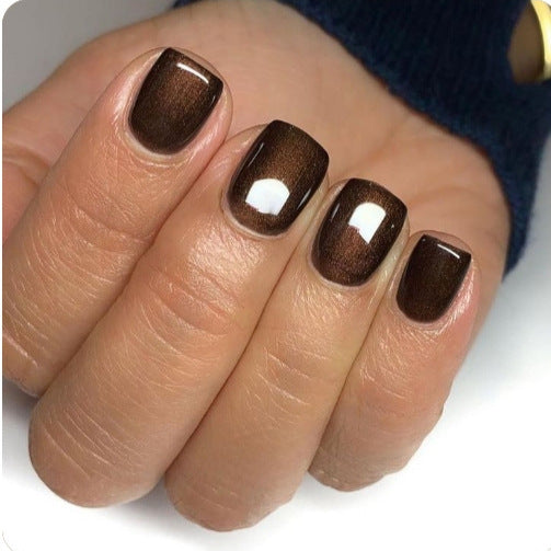 Close-up of a hand with brown nail polish on a white background