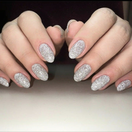 Close-up of hands with glittery silver nail polish on a neutral background