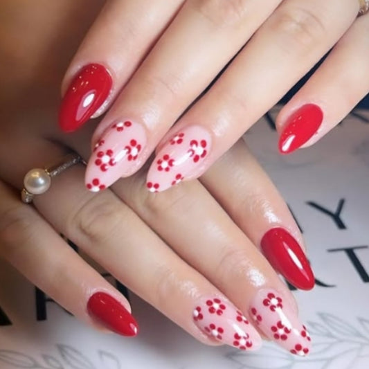 Close-up of a hand with red nail polish and floral designs on a blurred background
